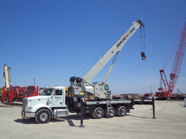 Maxim Crane boom trucks in a crane yard with a closeup of a boom truck with its boom extended.