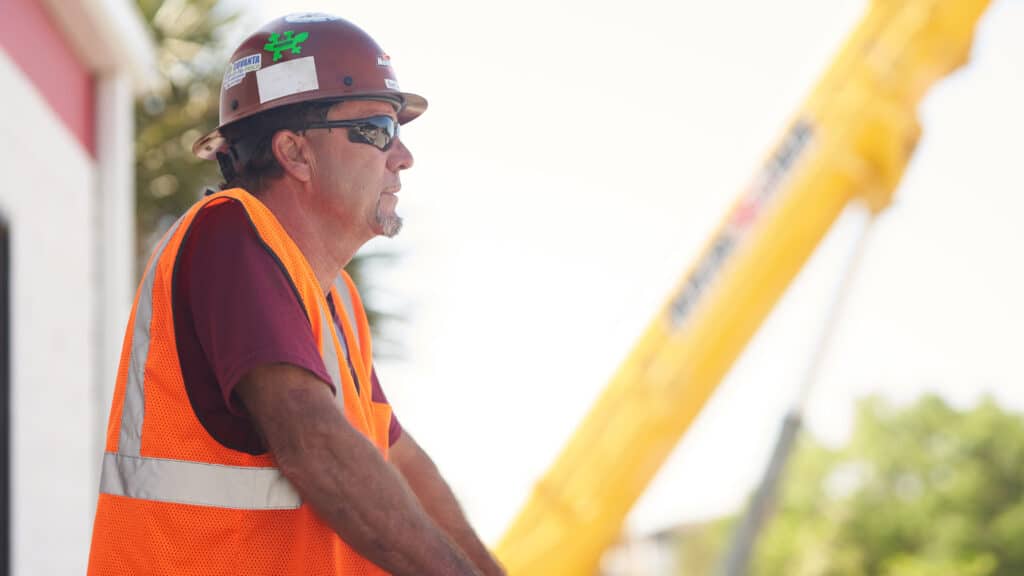 Construction project worker in the foreground with a Maxim Crane in the background