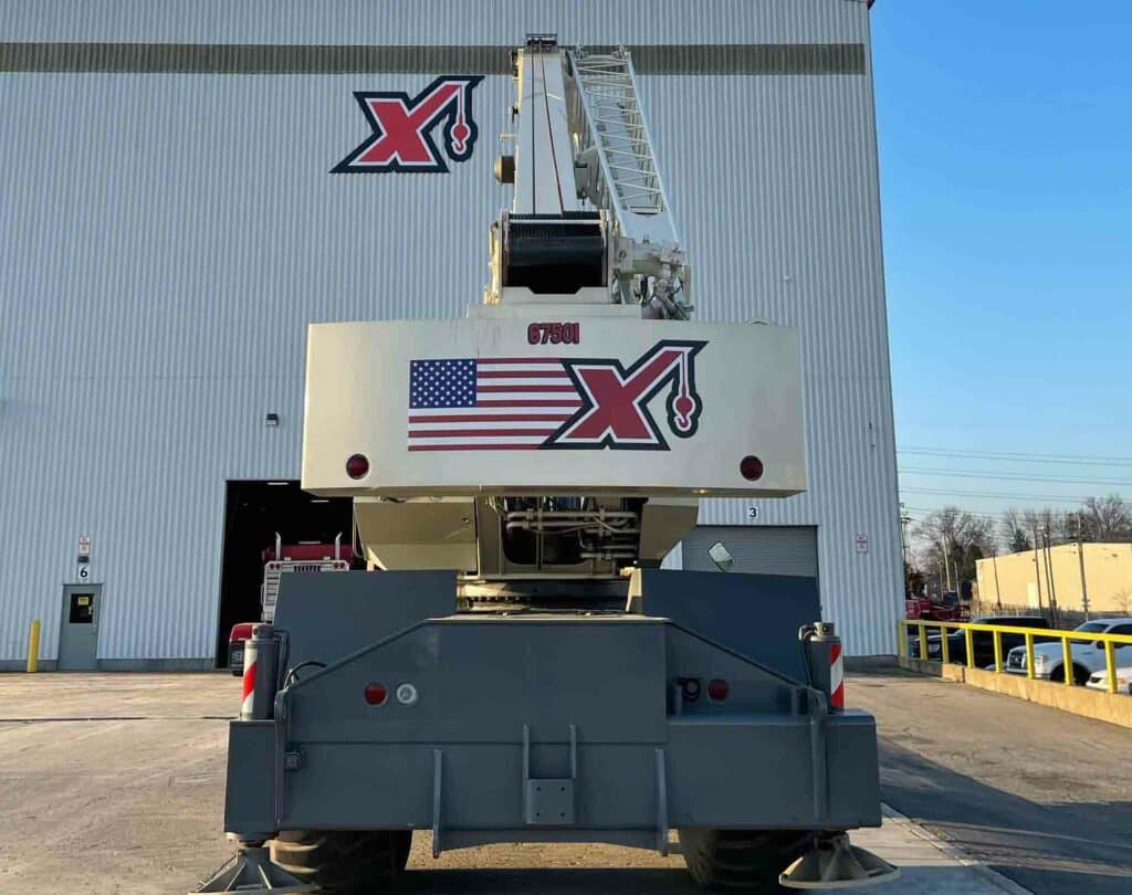 buying a used crane from Maxim Crane concept with front view of a crane for sale in a parking lot with the Maxim logo on it