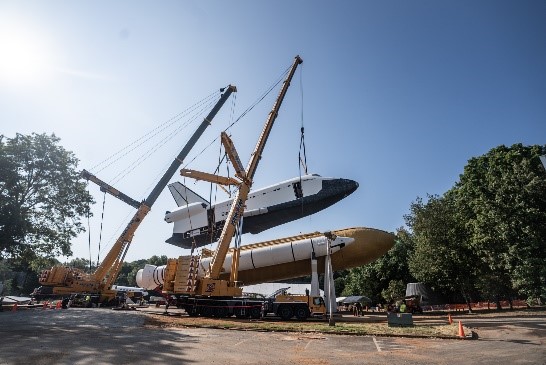 Rocket transport operation using cranes to lift spacecraft for assembly and relocation.