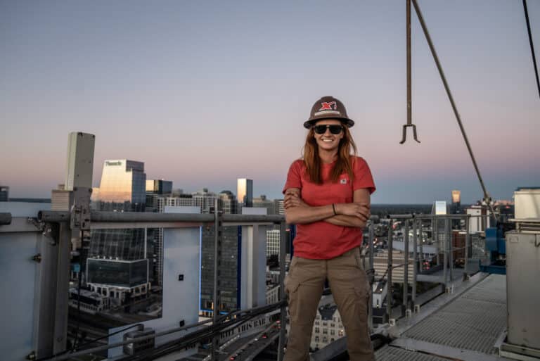 Construction worker enjoying sunset views from a high-rise building rooftop.