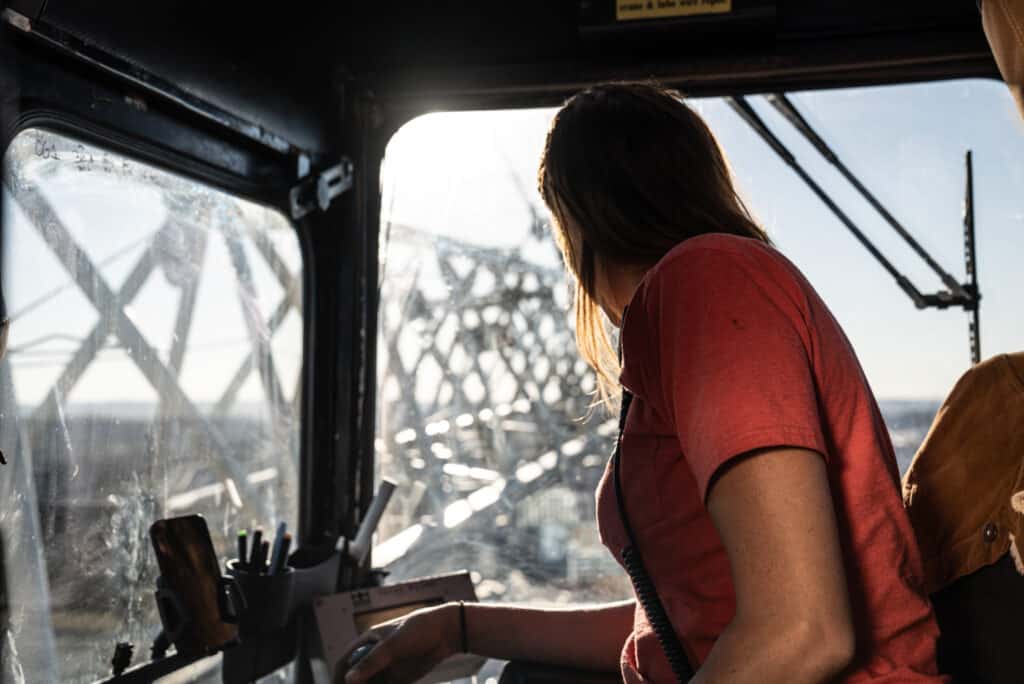 Crane operator at sunset working high above the ground, managing construction equipment.